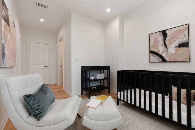 bedroom with light hardwood / wood-style floors and a crib