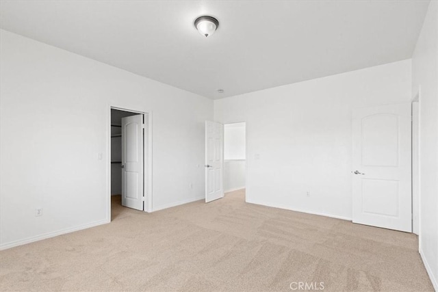 unfurnished bedroom featuring light colored carpet, a closet, and a walk in closet