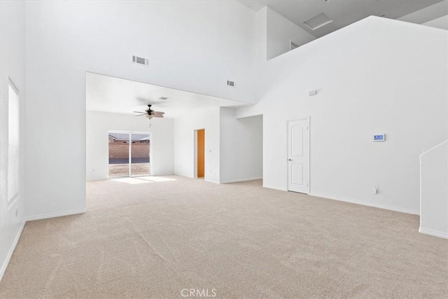 spare room featuring ceiling fan, a high ceiling, and light colored carpet