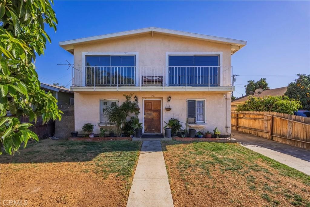 view of front of property with a balcony and a front lawn