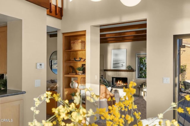 dining room with built in shelves, beamed ceiling, and a fireplace