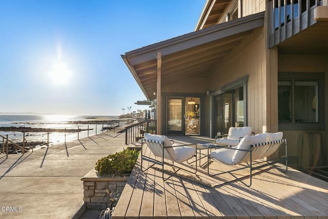 wooden deck with a water view and a beach view