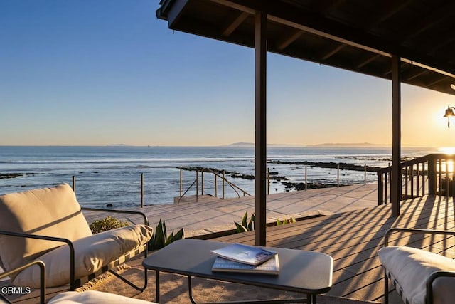 deck at dusk featuring a water view