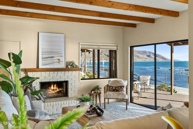 living room featuring beamed ceiling, a water and mountain view, and a brick fireplace