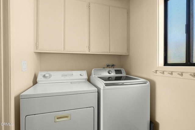 laundry room with washing machine and clothes dryer and cabinets