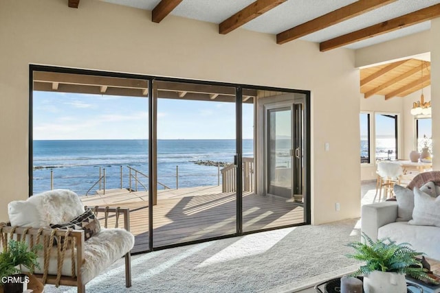 interior space with beam ceiling, a water view, and an inviting chandelier