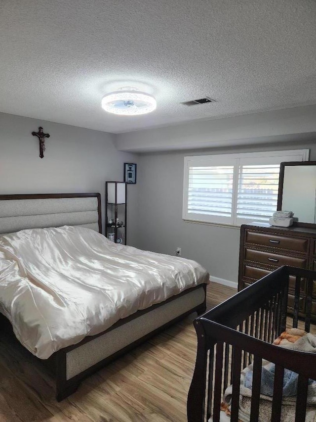 bedroom with hardwood / wood-style floors and a textured ceiling