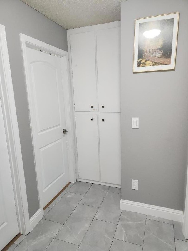 interior space with a textured ceiling, light tile patterned floors, and a closet