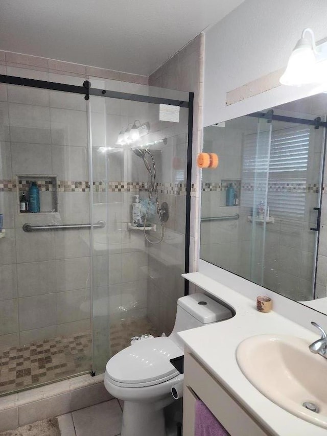 bathroom featuring a shower with shower door, tile patterned floors, vanity, and toilet