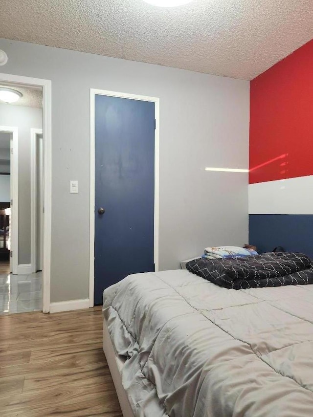 bedroom with a textured ceiling and wood-type flooring