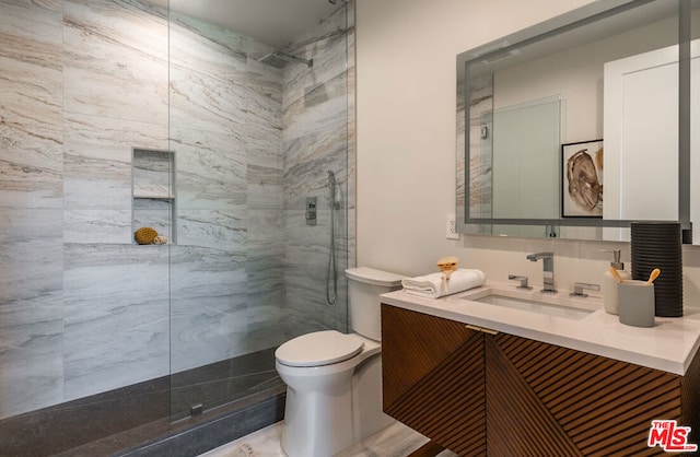 bathroom featuring toilet, a shower with shower door, and vanity