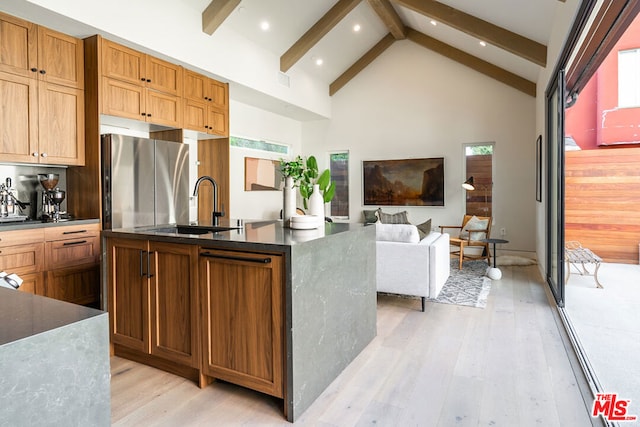 kitchen featuring sink, plenty of natural light, high vaulted ceiling, and stainless steel refrigerator