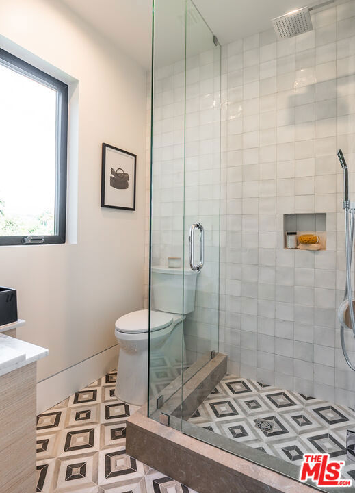 bathroom with a shower with shower door, toilet, and vanity