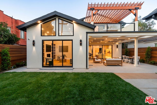 back house at dusk with a patio area, an outbuilding, a yard, and a pergola