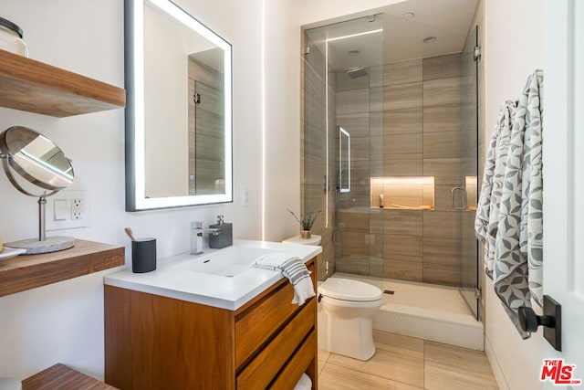 bathroom featuring toilet, a shower with door, and vanity