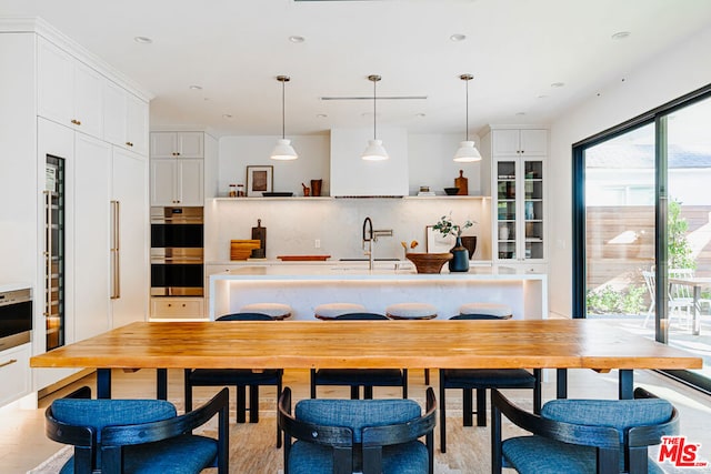 kitchen featuring sink, white cabinets, and hanging light fixtures