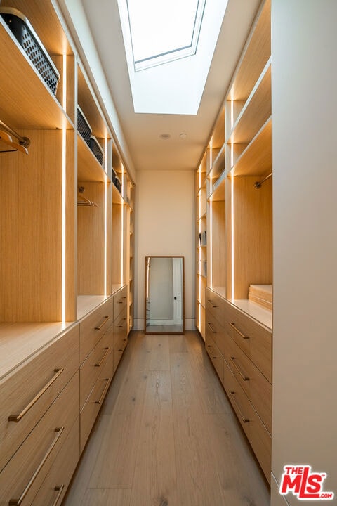 walk in closet featuring light hardwood / wood-style floors and a skylight