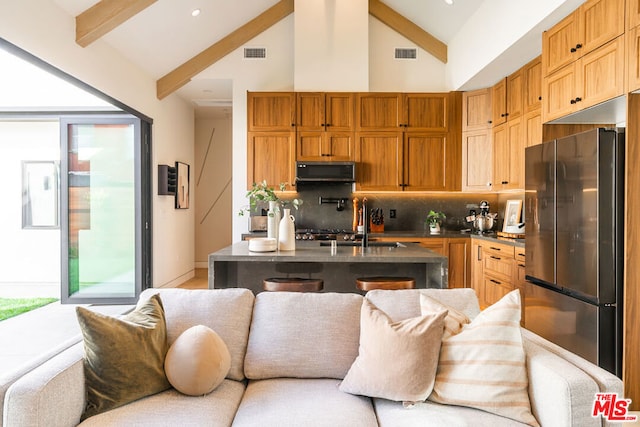 kitchen with beamed ceiling, stainless steel refrigerator, tasteful backsplash, and high vaulted ceiling