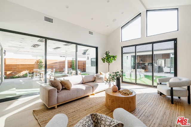 living room featuring high vaulted ceiling and a healthy amount of sunlight