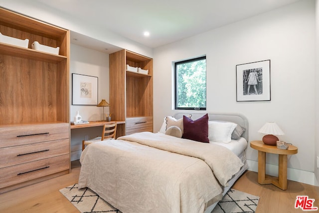 bedroom with built in desk and light hardwood / wood-style floors