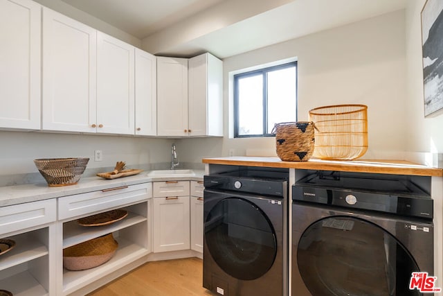 washroom featuring sink, cabinets, light hardwood / wood-style flooring, and washing machine and dryer