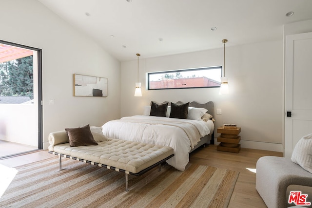 bedroom featuring light hardwood / wood-style floors, vaulted ceiling, and access to outside