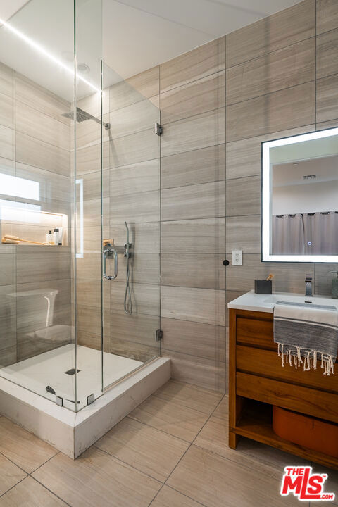 bathroom with vanity, an enclosed shower, tile patterned floors, and tile walls