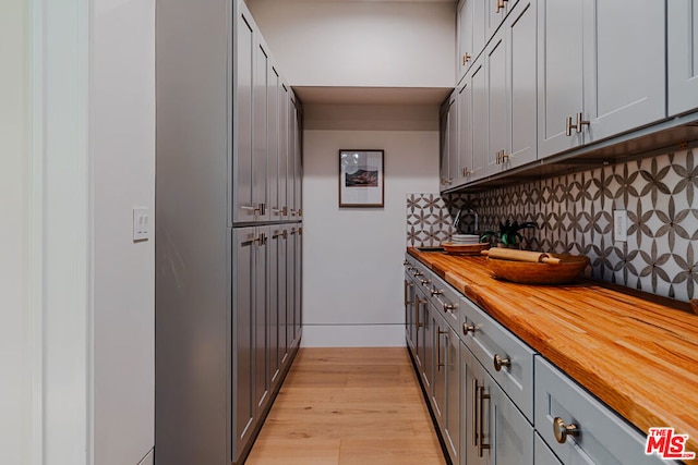 kitchen with gray cabinets, tasteful backsplash, light hardwood / wood-style flooring, and butcher block countertops