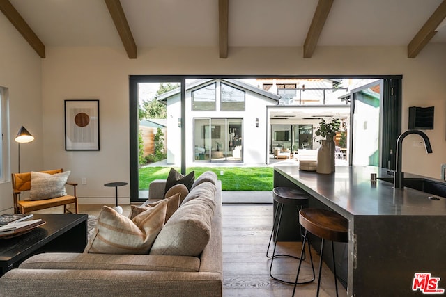 living room featuring sink, light wood-type flooring, and beam ceiling