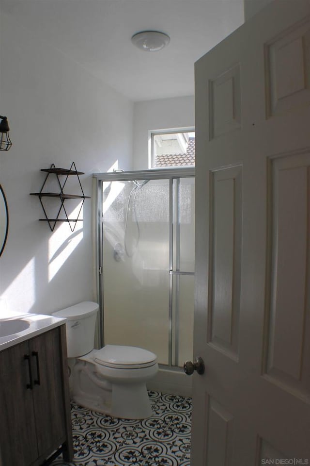 bathroom featuring toilet, walk in shower, vanity, and tile patterned flooring