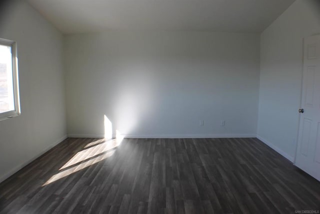 spare room featuring dark hardwood / wood-style floors and lofted ceiling