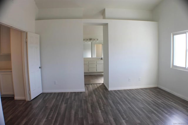 unfurnished bedroom with connected bathroom and dark hardwood / wood-style floors