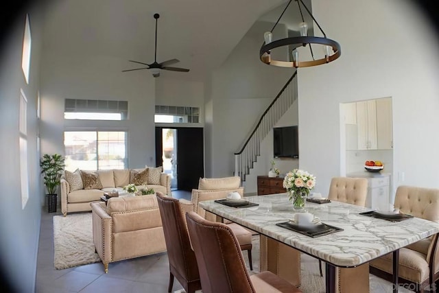 dining space with high vaulted ceiling and ceiling fan with notable chandelier