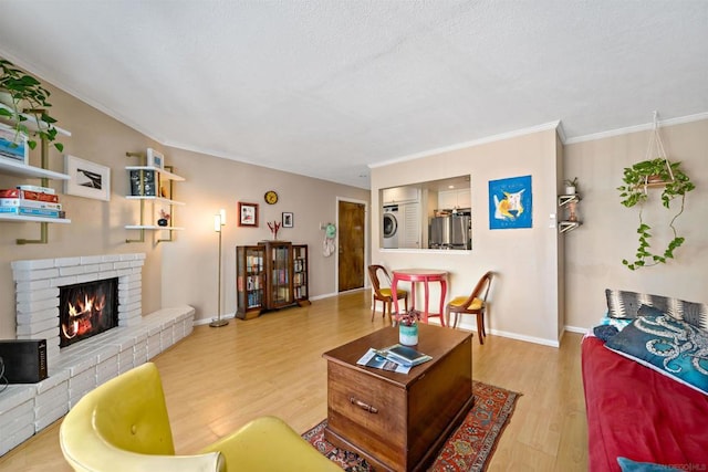 living room with wood-type flooring, stacked washer and dryer, a brick fireplace, and ornamental molding