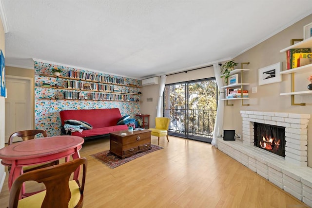 living room with hardwood / wood-style flooring, an AC wall unit, crown molding, and a fireplace