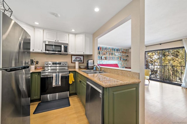 kitchen with light hardwood / wood-style flooring, appliances with stainless steel finishes, sink, white cabinets, and green cabinetry