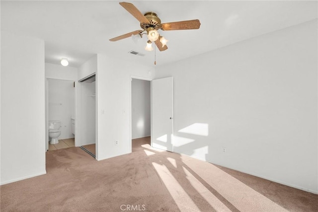 unfurnished bedroom featuring ceiling fan, connected bathroom, a closet, and light carpet