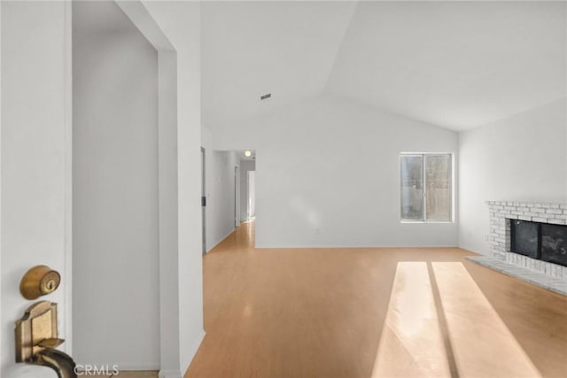 unfurnished living room featuring light hardwood / wood-style floors, a fireplace, and lofted ceiling