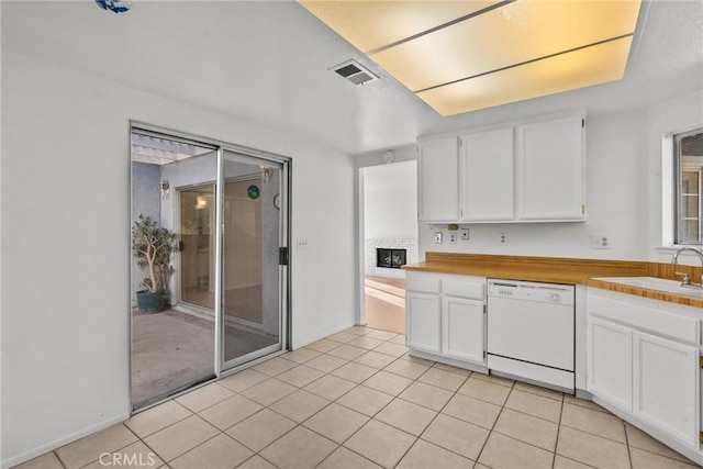 kitchen featuring sink, white cabinetry, dishwasher, and a brick fireplace