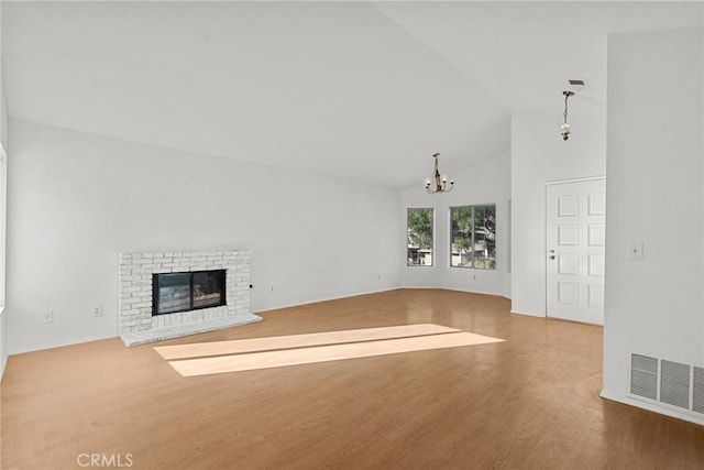 unfurnished living room featuring an inviting chandelier, wood-type flooring, lofted ceiling, and a fireplace