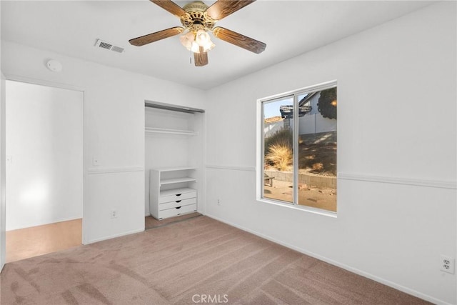 unfurnished bedroom featuring light carpet, a closet, and ceiling fan