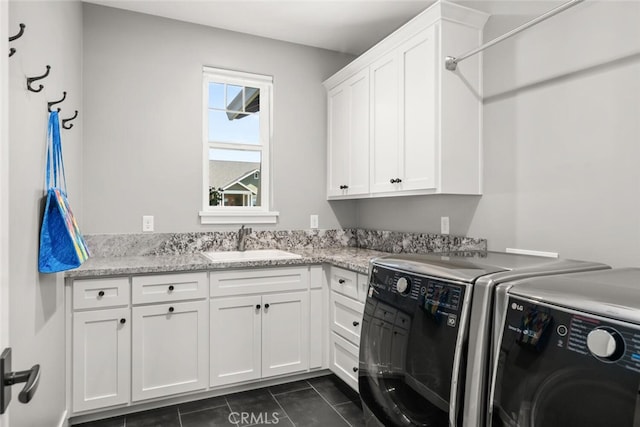 clothes washing area with sink, cabinets, washer and clothes dryer, and dark tile patterned floors