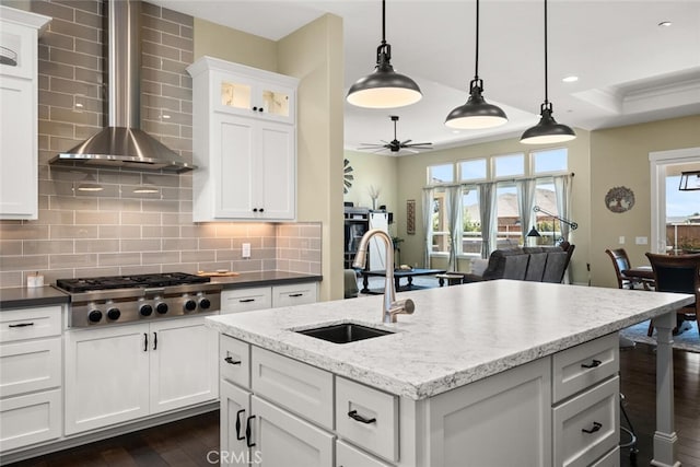 kitchen with wall chimney exhaust hood, tasteful backsplash, sink, hanging light fixtures, and stainless steel gas cooktop