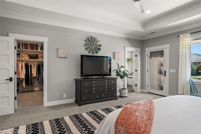 bedroom with a spacious closet, a closet, ornamental molding, light colored carpet, and a tray ceiling