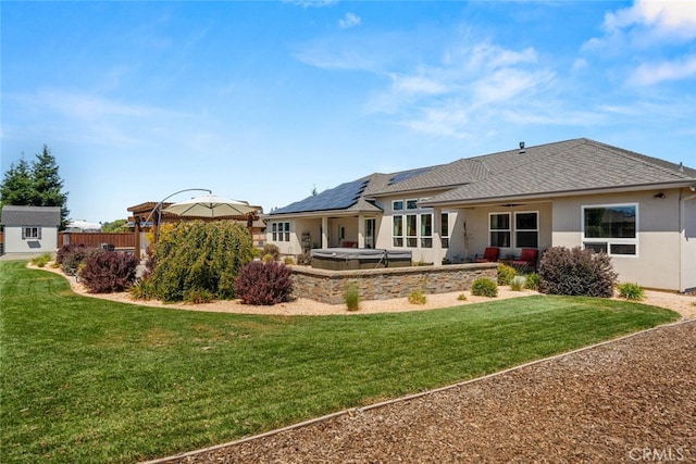 rear view of house featuring a lawn, a gazebo, solar panels, and a hot tub