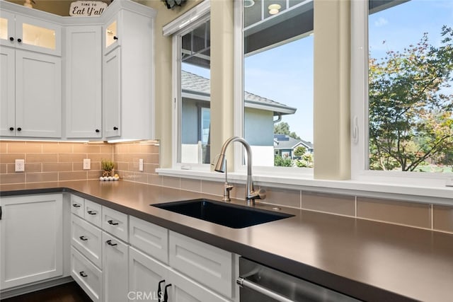 kitchen with sink, white cabinetry, stainless steel dishwasher, and tasteful backsplash