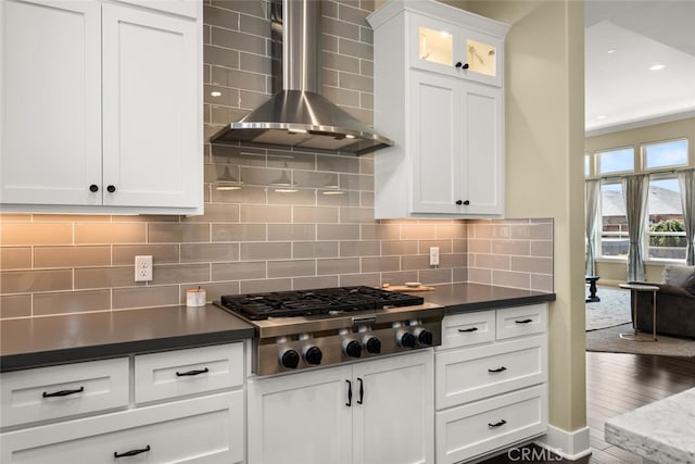 kitchen featuring dark hardwood / wood-style flooring, wall chimney exhaust hood, white cabinetry, decorative backsplash, and stainless steel gas cooktop