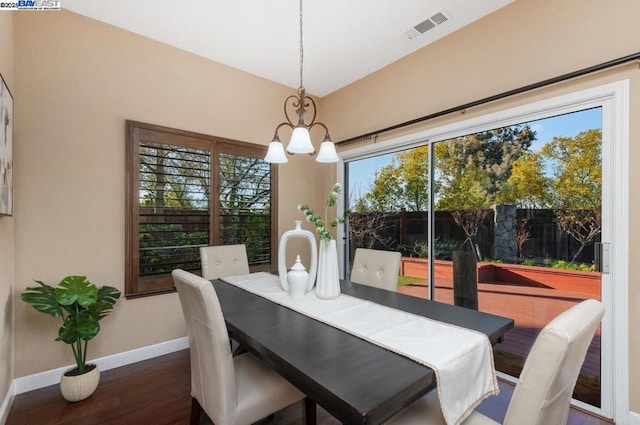 dining space featuring dark wood-type flooring and a chandelier