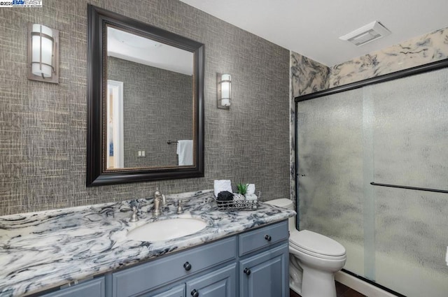 bathroom with vanity, a shower with door, and toilet