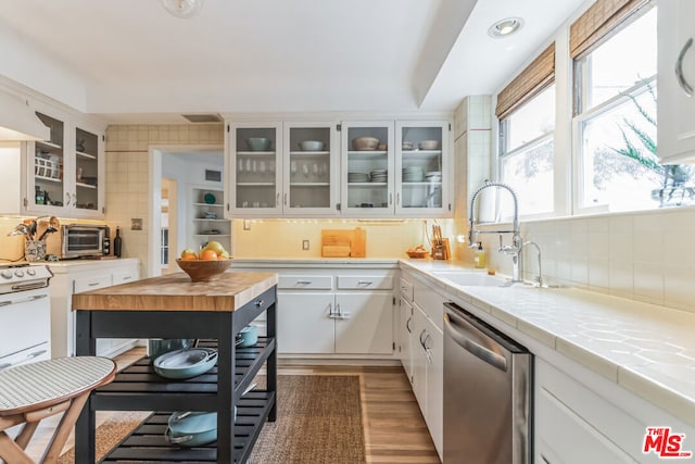 kitchen with sink, white cabinetry, tile counters, dark hardwood / wood-style flooring, and stainless steel dishwasher